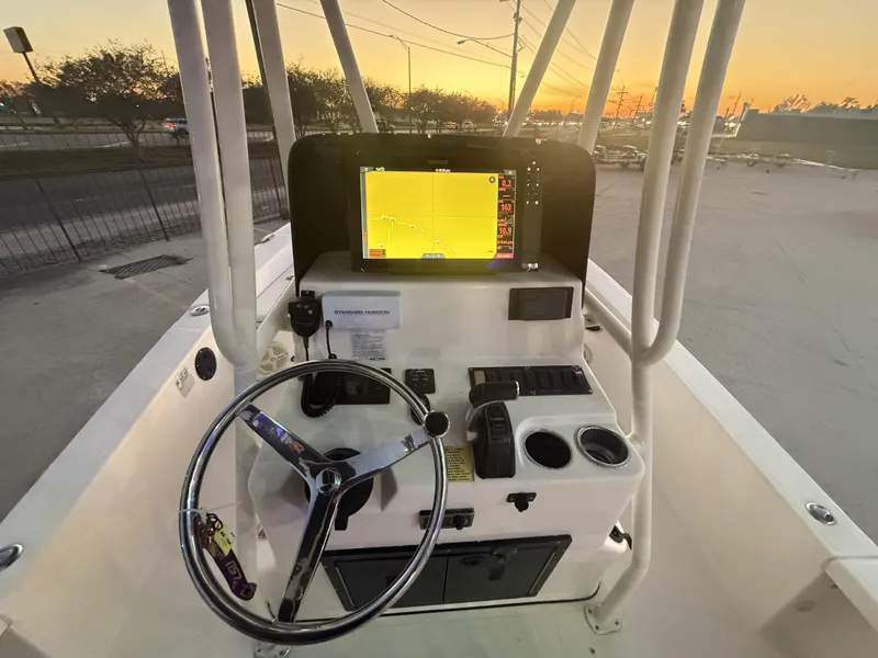 Slide: The Image of 2013 BlackJack 224 boat console with steering wheel and navigation screen at sunset. - 2