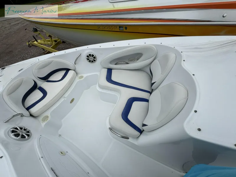 Slide: The Image of 2002 Baja 292 Islander boat with white and blue seating, docked beside a yellow trailer. - 19