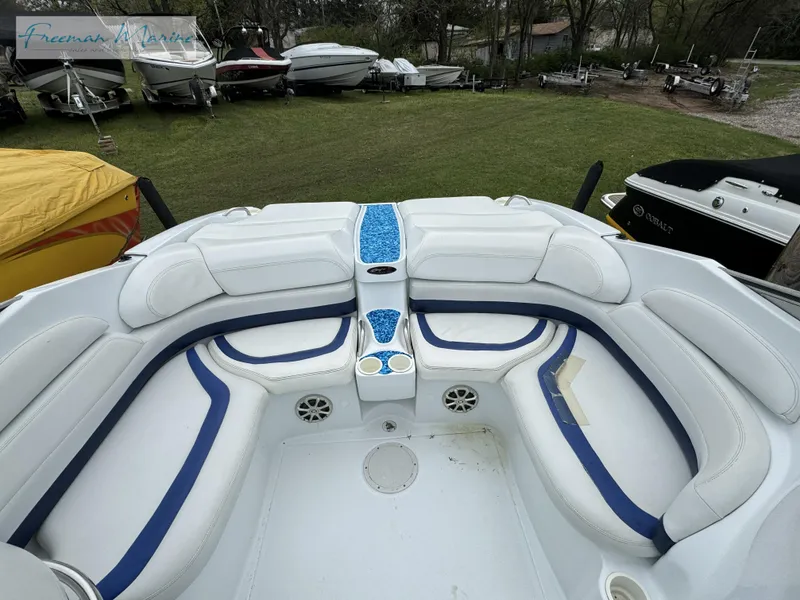 Slide: The Image of 2002 Baja 292 Islander boat interior with white and blue seating, parked on grass. - 8