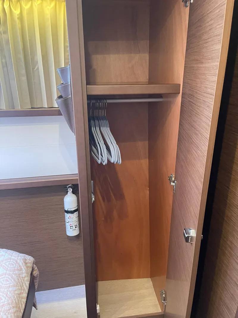 Slide: The Image of Open wooden closet with hangers inside a 2019 Lagoon 450 F yacht cabin. - 19