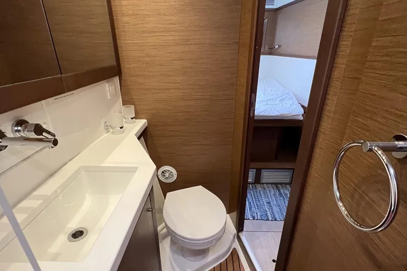 Slide: The Image of 2019 Lagoon 450 F yacht bathroom with sink, toilet, and adjacent bedroom. - 26