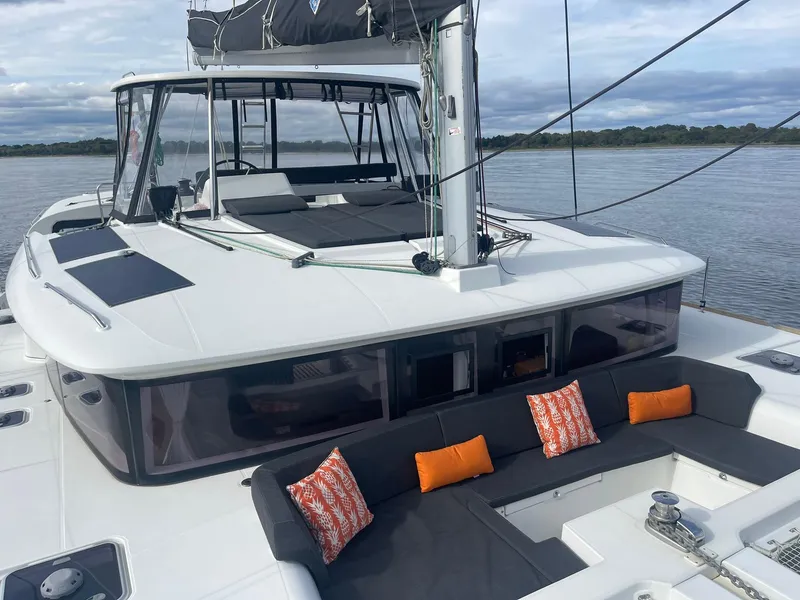 Slide: The Image of 2019 Lagoon 450 F catamaran with spacious deck, colorful cushions, and scenic water backdrop. - 28