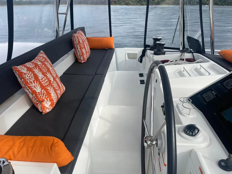 Slide: The Image of 2019 Lagoon 450 F yacht interior with orange cushions and steering wheel, overlooking calm waters. - 29
