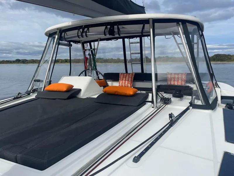 Slide: The Image of 2019 Lagoon 450 F catamaran with cushioned deck, orange pillows, and scenic water view. - 31