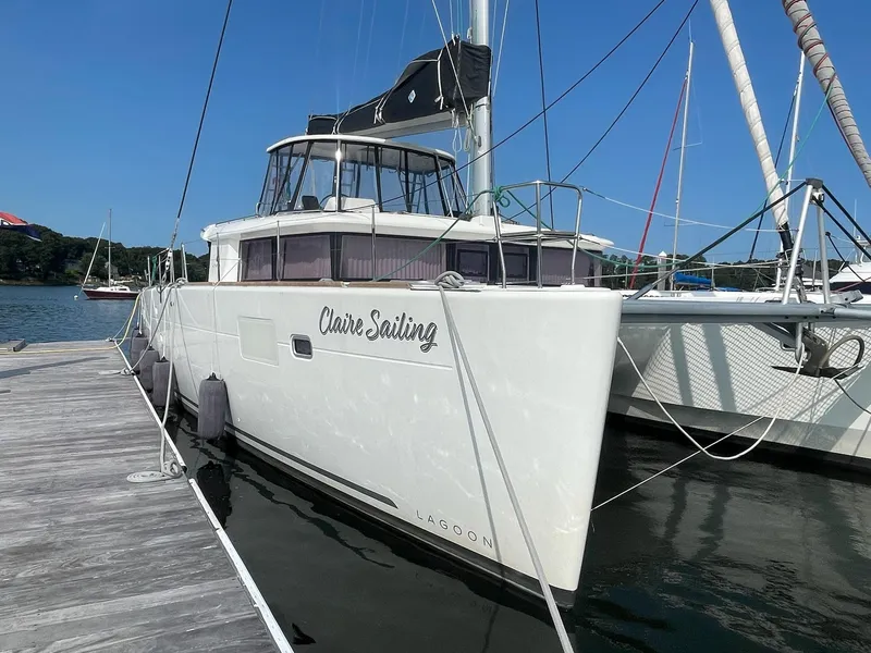 Slide: The Image of 2019 Lagoon 450 F catamaran docked, named "Claire Sailing," under clear blue sky. - 4