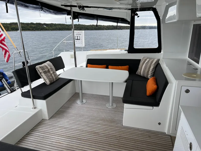 Slide: The Image of 2019 Lagoon 450 F yacht interior with seating, table, and cushions on a serene water backdrop. - 40