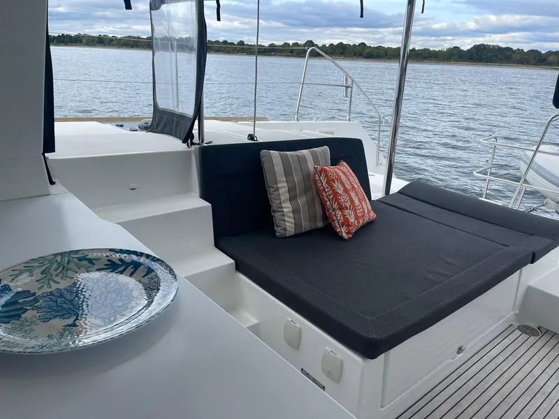 Slide: The Image of 2019 Lagoon 450 F yacht deck with cushioned seating and decorative pillows by the water. - 42