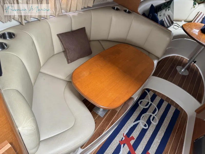 Slide: The Image of 2008 Chaparral Signature 290 interior with curved seating, wooden table, and nautical-themed rug. - 23