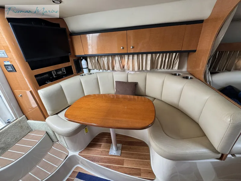 Slide: The Image of 2008 Chaparral Signature 290 interior with curved seating, wooden table, and mounted TV. - 30