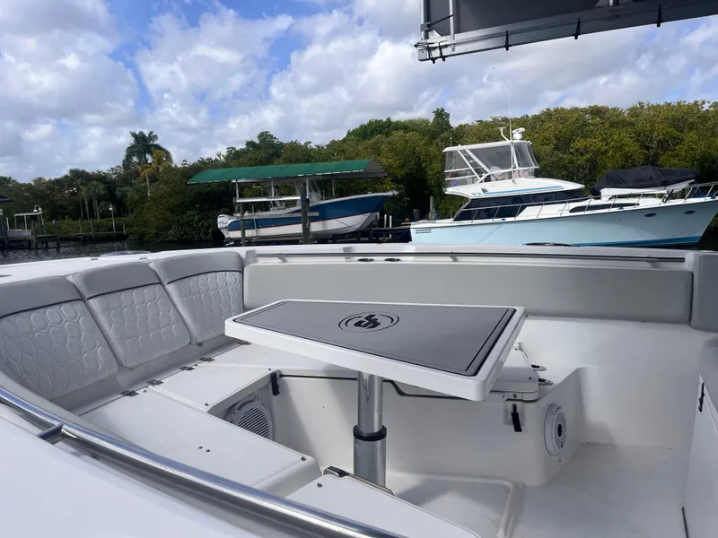 Slide: The Image of 2021 Sea Fox 368 Commander boat interior with seating and table, docked near other boats. - 16