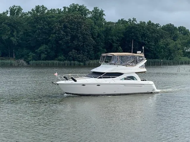 Slide: The Image of 2001 Maxum 4100 SCB yacht cruising on a calm lake with forested shoreline. - 0