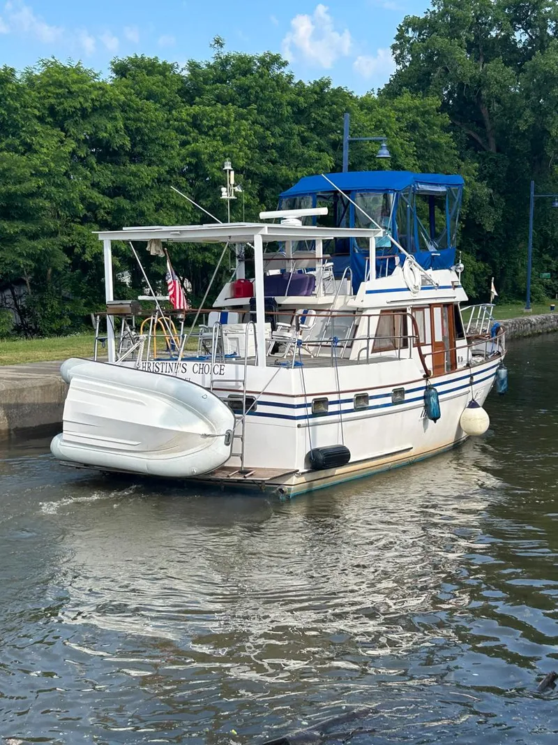 Slide: The Image of 1983 Lindmark 39 Trawler in a canal, surrounded by lush greenery. - 1