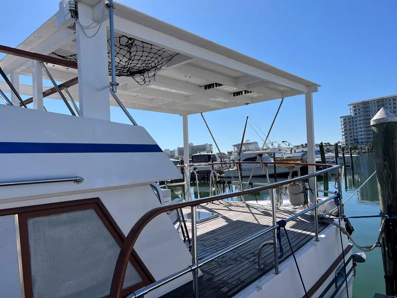 Slide: The Image of 1983 Lindmark 39 Trawler docked at marina, featuring upper deck and railing. - 10