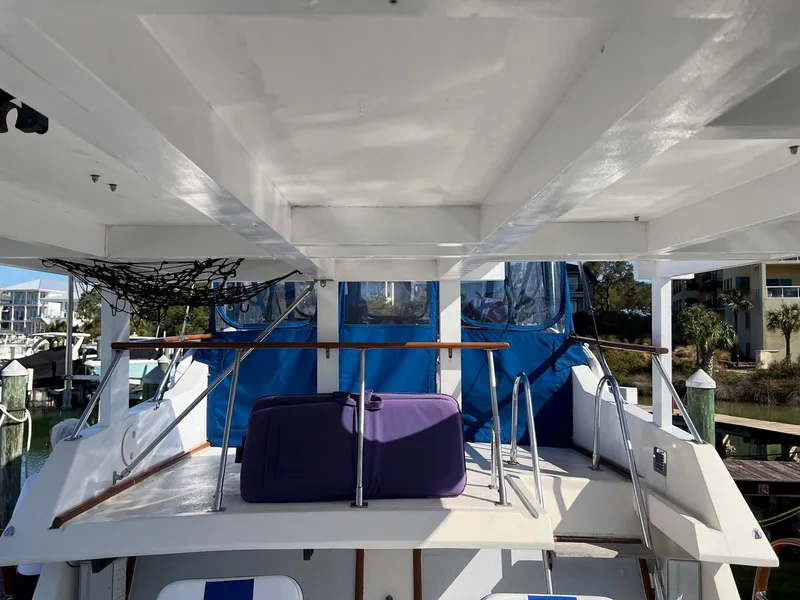 Slide: The Image of 1983 Lindmark 39 Trawler with blue cover and purple luggage on deck. - 26