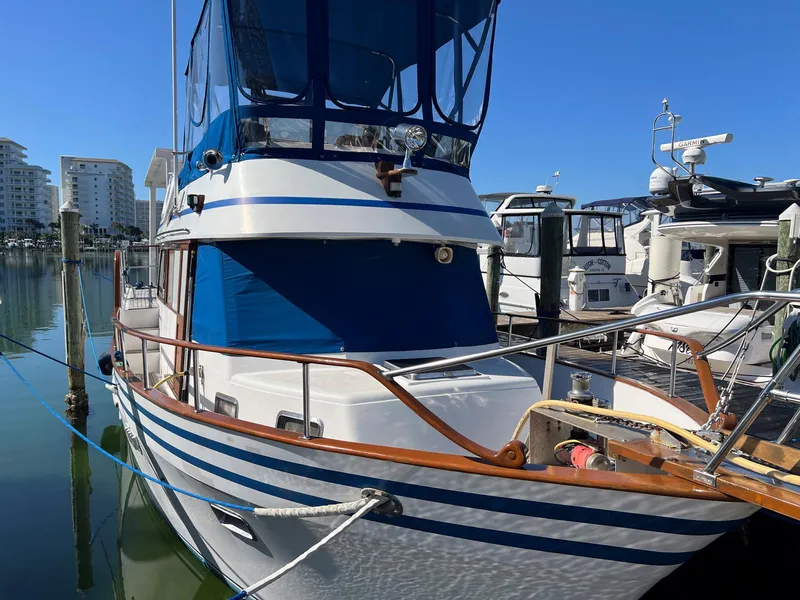 Slide: The Image of 1983 Lindmark 39 Trawler docked at marina, featuring blue and white exterior. - 3