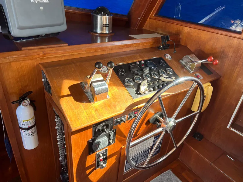 Slide: The Image of Control panel of a 1983 Lindmark 39 Trawler with steering wheel and navigation instruments. - 48