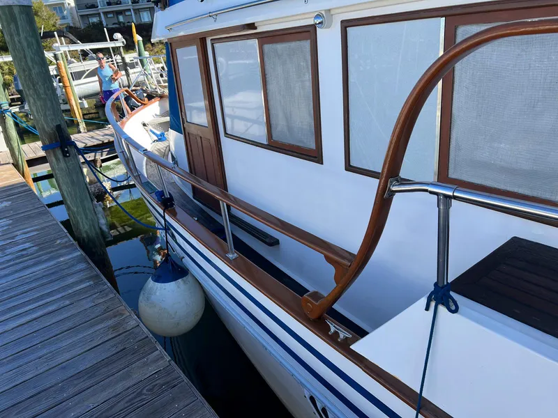 Slide: The Image of 1983 Lindmark 39 Trawler docked, showcasing wooden railings and windows. - 6