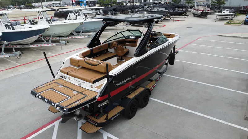 Slide: The Image of 2022 Chaparral 28 Surf boat on trailer in parking lot, surrounded by other boats. - 10
