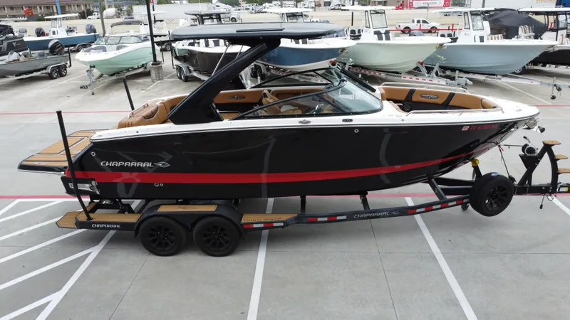 Slide: The Image of 2022 Chaparral 28 Surf boat on trailer, black with red accents, parked in marina. - 11