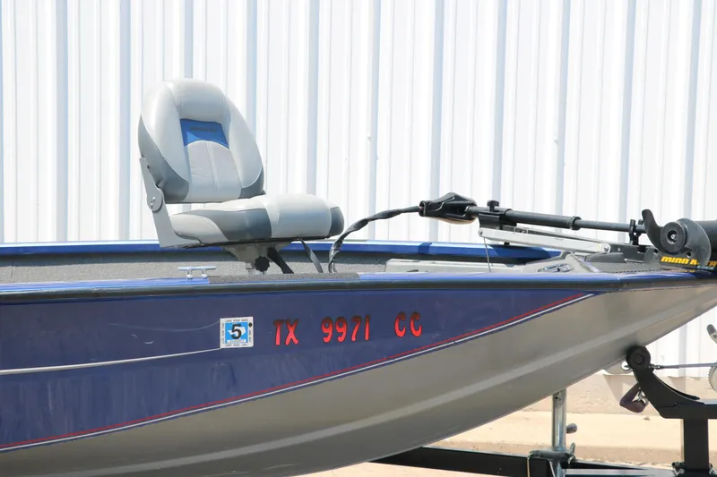 Slide: The Image of 2014 Bass Tracker PT175TF boat with registration number, parked near a white wall. - 25
