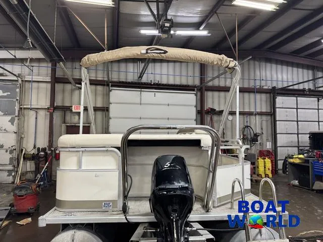 Slide: The Image of 2008 SunChaser 8522 pontoon boat in a garage, featuring a covered canopy and outboard motor. - 32