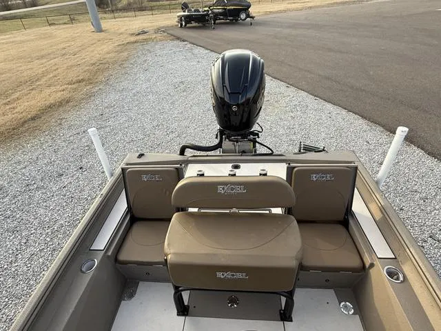 Slide: The Image of 2022 Excel Boats Bay Pro 220 with seating and outboard motor, parked on gravel. - 5