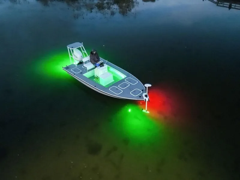 Slide: The Image of A 1999 Flats and Bay 18x8 boat with vibrant green and red underwater lights. - 3