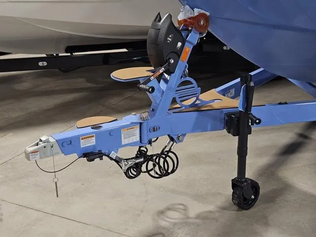 Slide: The Image of Trailer hitch of 2025 Malibu 23 LSV boat, featuring blue frame and safety chains. - 10