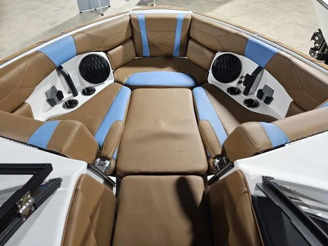 Slide: The Image of 2025 Malibu 23 LSV boat interior with brown and blue seating, cup holders, and speakers. - 17