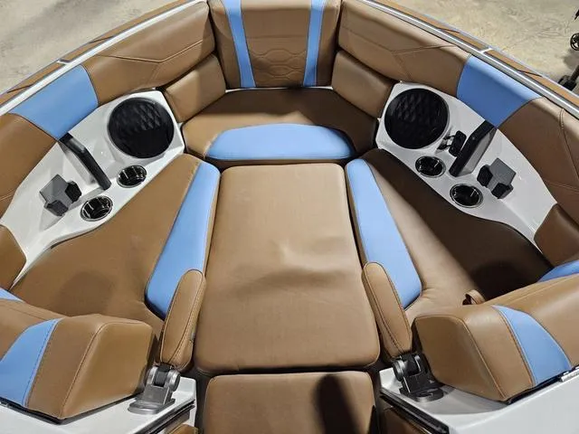 Slide: The Image of Interior of 2025 Malibu 23 LSV boat with brown and blue seating, cup holders, and speakers. - 20