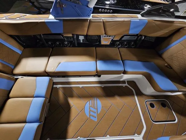 Slide: The Image of 2025 Malibu 23 LSV interior with brown and blue seating, stylish design, and logo detailing. - 27