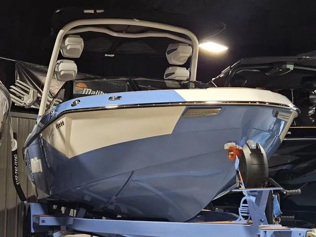 Slide: The Image of 2025 Malibu 23 LSV boat in showroom, blue and white design, on trailer. - 3