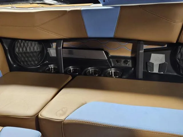 Slide: The Image of Interior of 2025 Malibu 23 LSV boat with brown and blue seating, cup holders, and speaker. - 31