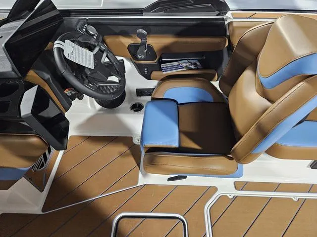 Slide: The Image of 2025 Malibu 23 LSV boat interior with brown and blue seating, modern steering, and controls. - 35