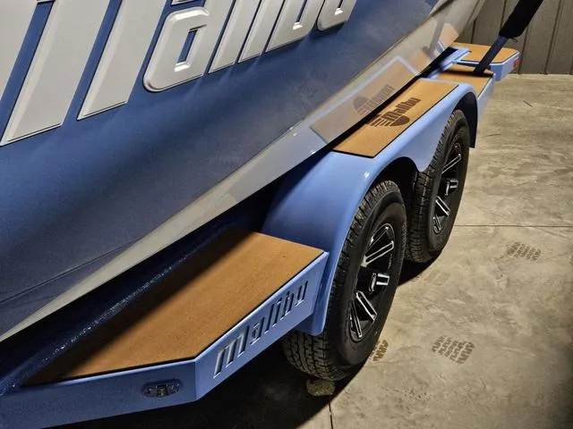Slide: The Image of 2025 Malibu 23 LSV boat trailer with custom wheels and blue accents. - 7