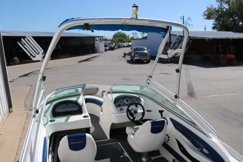 Slide: The Image of 2011 Sea Ray 205 Sport boat interior with steering wheel and seating, parked outdoors. - 17