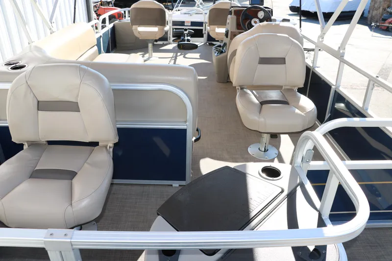 Slide: The Image of 2023 Sun Tracker 18 BASS BUGGY pontoon boat interior with beige seating and steering console. - 18