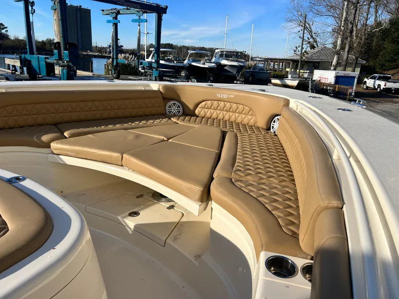 Slide: The Image of 2017 Scout 420 LXF boat with tan leather seating and cup holders, docked at a marina. - 11