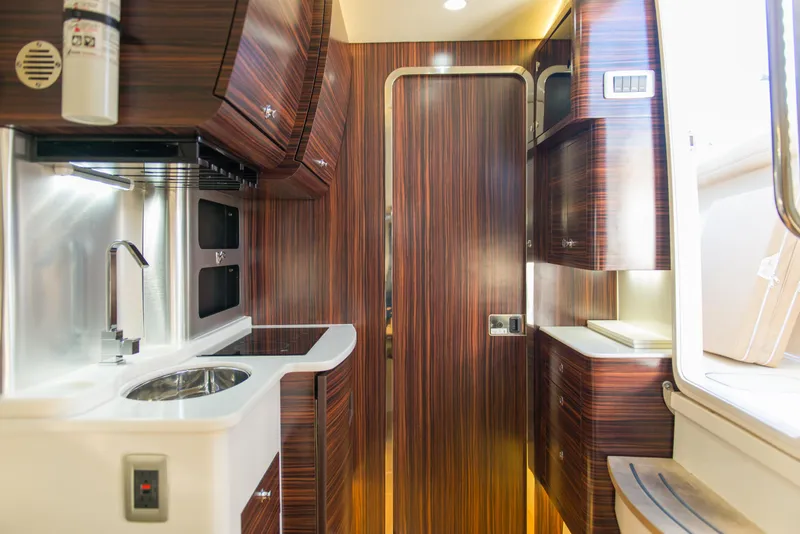 Slide: The Image of Interior of 2017 Scout 420 LXF boat with modern wood finish and compact kitchen area. - 15