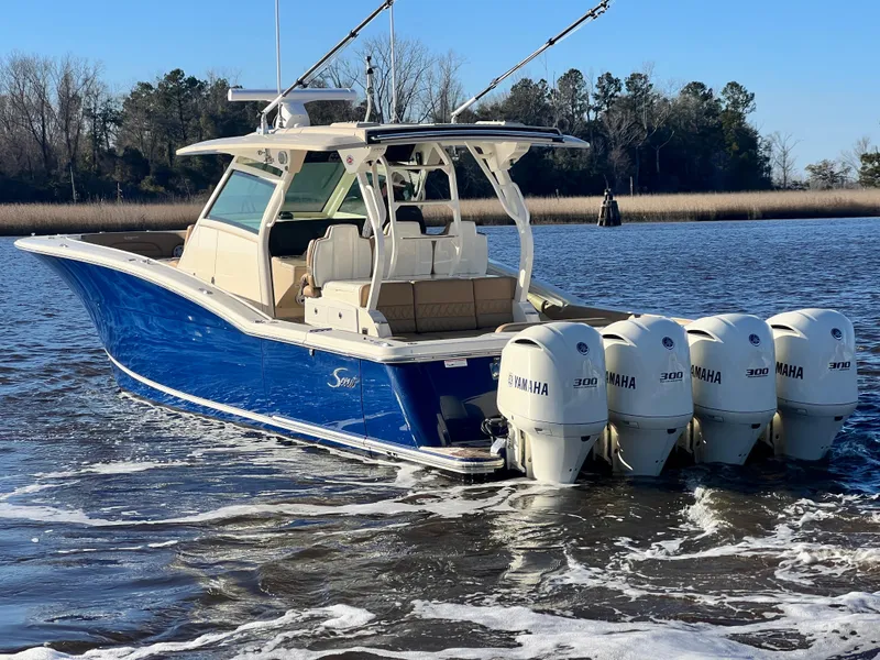 Slide: The Image of 2017 Scout 420 LXF boat with four Yamaha engines on a calm river. - 2