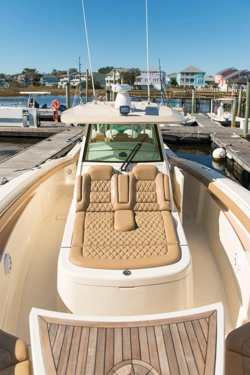 Slide: The Image of 2017 Scout 420 LXF luxury boat with tan seating at a marina. - 29