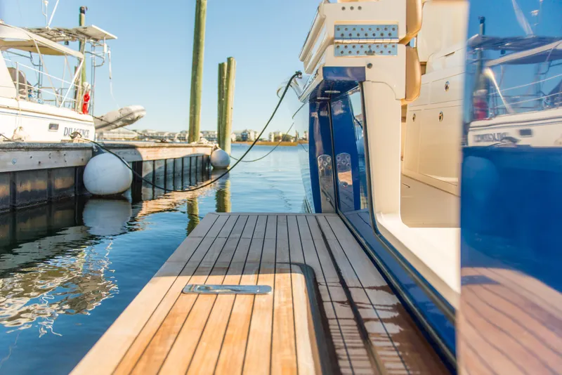 Slide: The Image of 2017 Scout 420 LXF yacht docked, showcasing sleek wooden deck and modern design. - 43