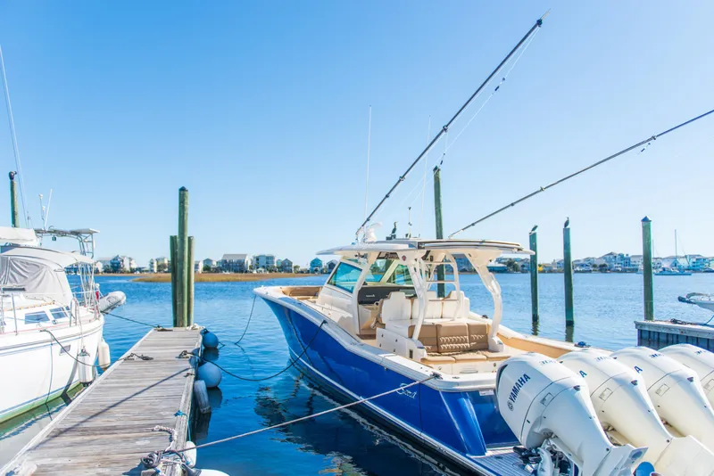 Slide: The Image of 2017 Scout 420 LXF boat docked with clear blue sky background. - 46