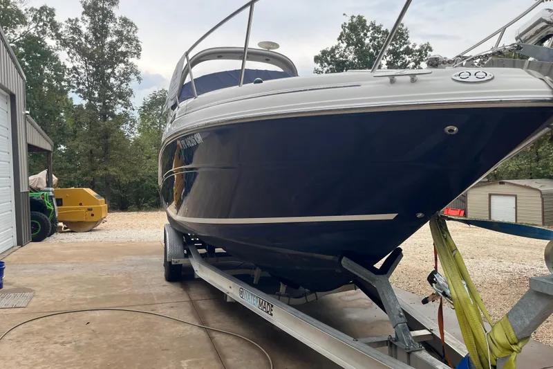 Slide: The Image of 2005 Sea Ray 280 Sundancer boat on trailer, parked outdoors near trees and a building. - 11