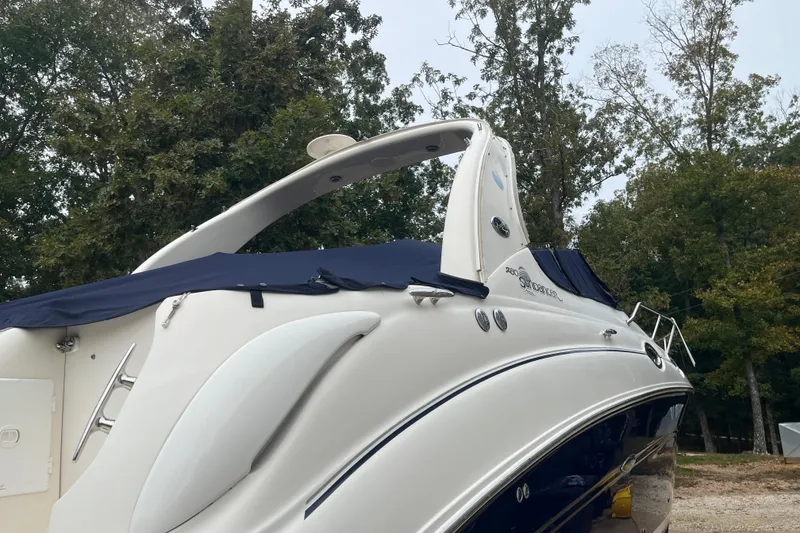 Slide: The Image of 2005 Sea Ray 280 Sundancer boat with blue cover, surrounded by trees. - 13