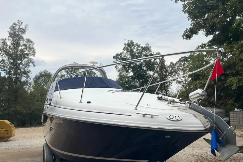 Slide: The Image of 2005 Sea Ray 280 Sundancer boat on trailer, surrounded by trees, under cloudy sky. - 17