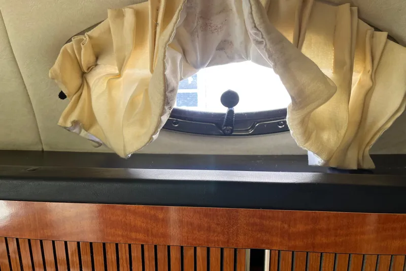 Slide: The Image of Interior view of a 2005 Sea Ray Sundancer 280 with a porthole and curtain. - 24