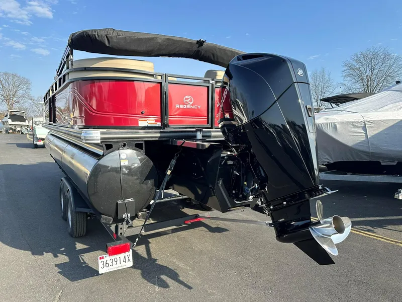 Slide: The Image of 2023 Regency 230 DL3 pontoon boat with powerful outboard motor, parked on trailer. - 6
