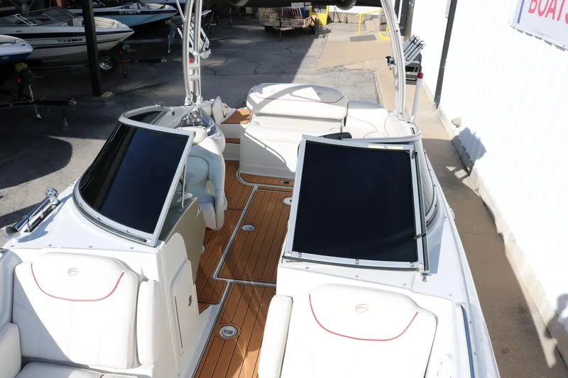 Slide: The Image of 2007 Crownline 240 EX boat with white seating and wooden deck, docked outdoors. - 23