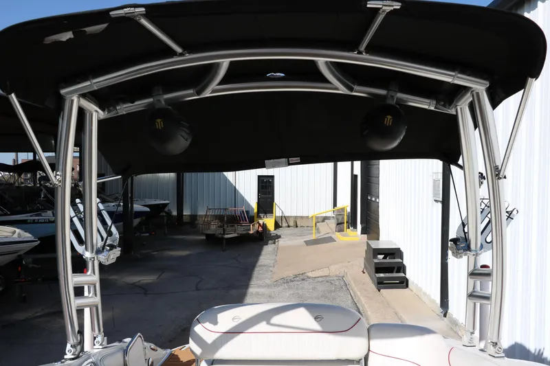 Slide: The Image of 2007 Crownline 240 EX boat with black canopy and metal frame in a storage area. - 26
